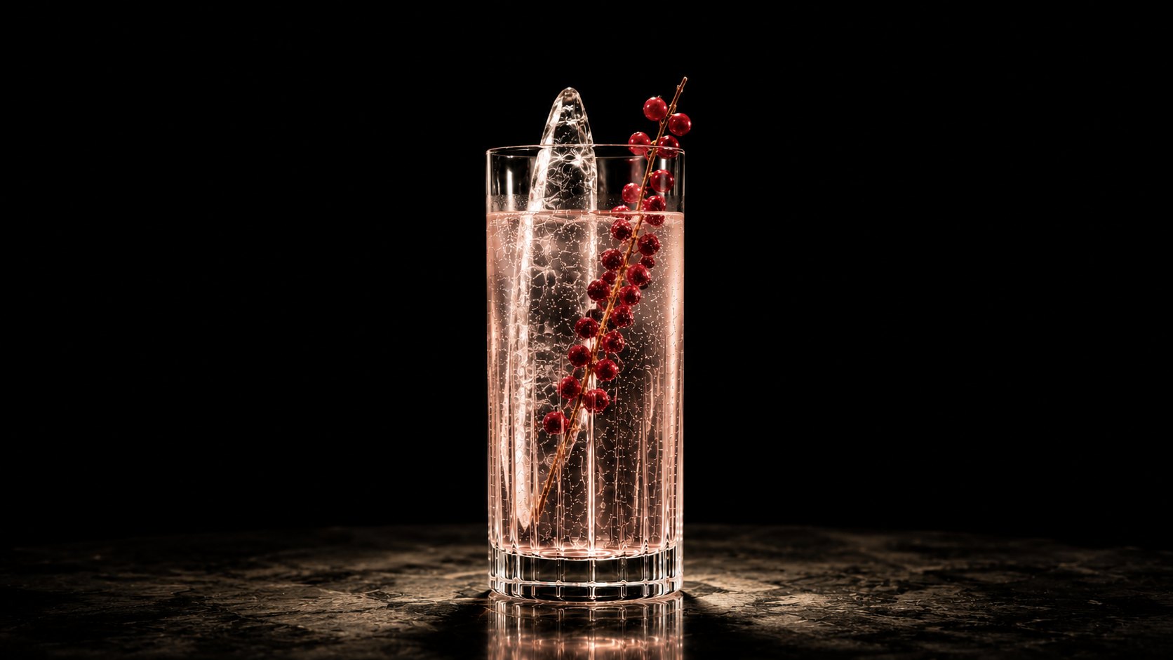 A blush-coloured highball with a clear ice spear and a trailing sprig of redcurrants.
