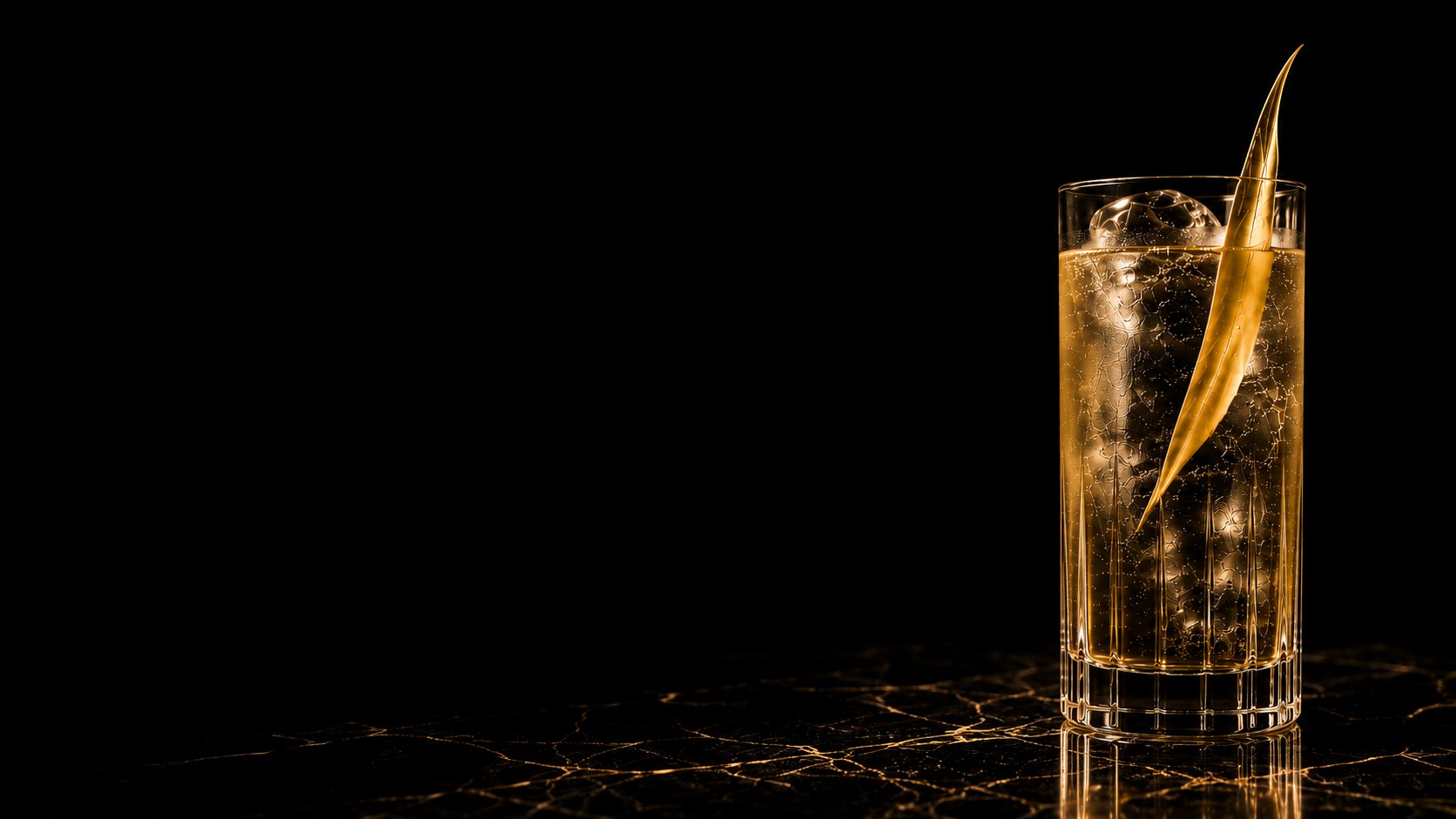 A highball served over ice with a gold citrus twist, lit against black.